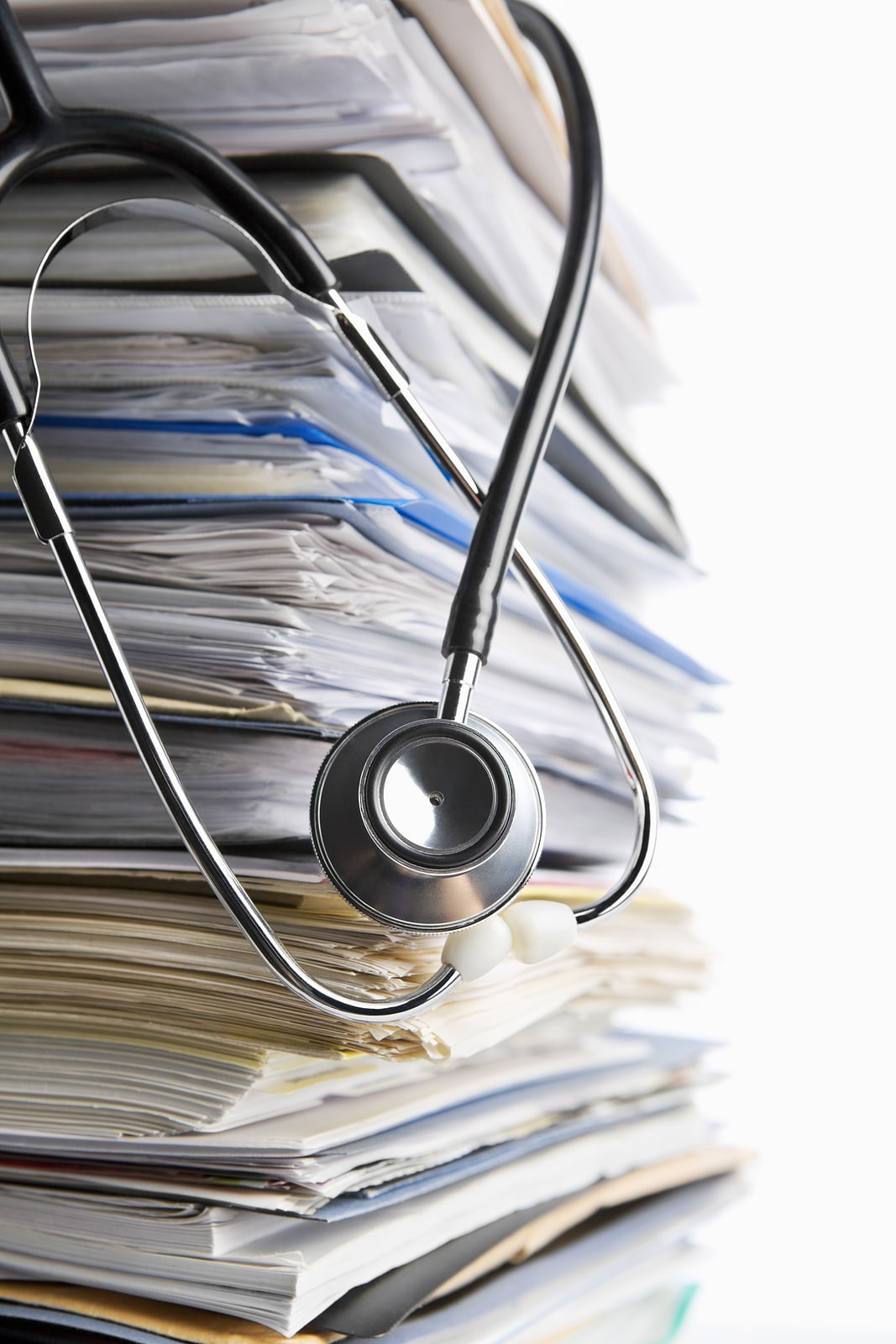 A stethoscope hangs over the top of a pile of medical records.